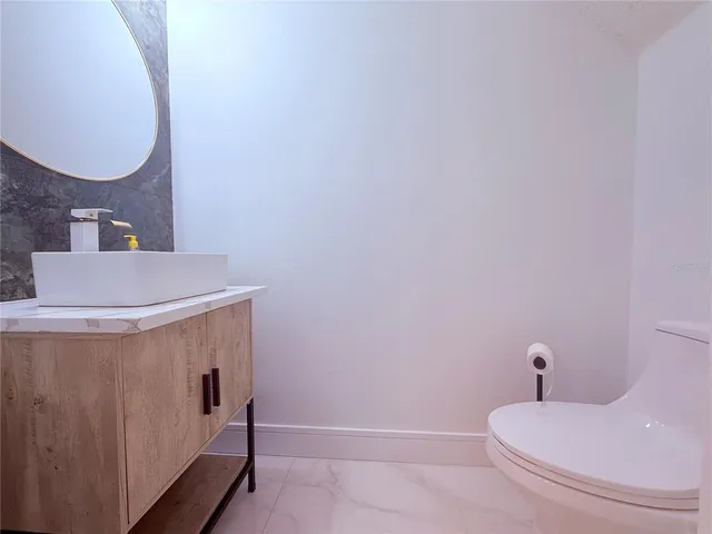 a bathroom with a granite countertop sink a toilet a mirror and shower