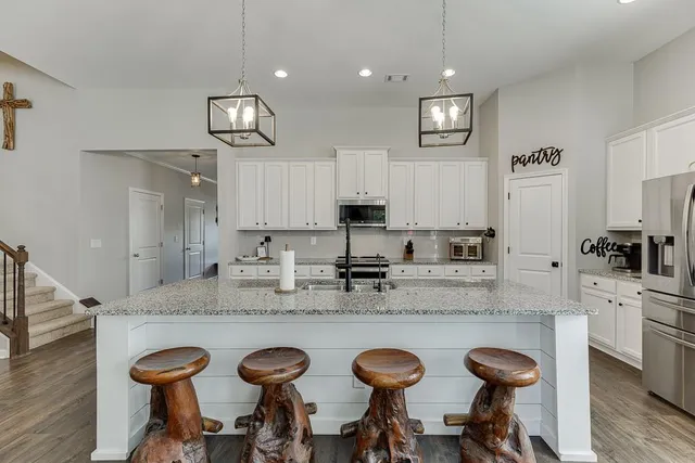 a kitchen with granite countertop a table chairs stove and cabinets