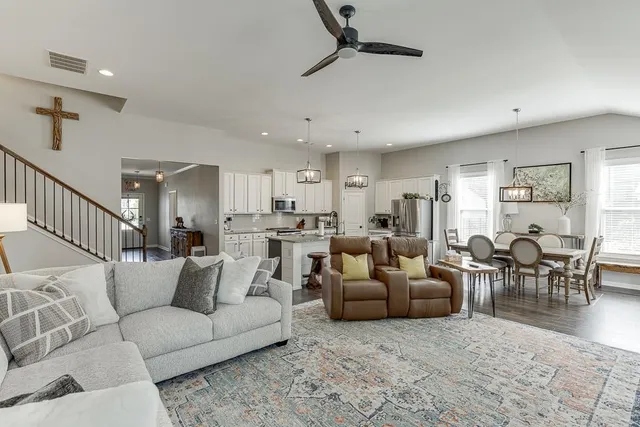 a living room with furniture and a dining table with wooden floor