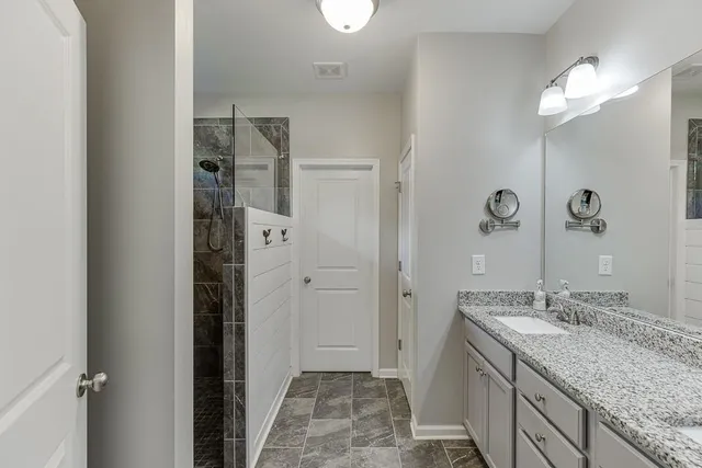 a bathroom with a granite countertop sink a shower and a mirror