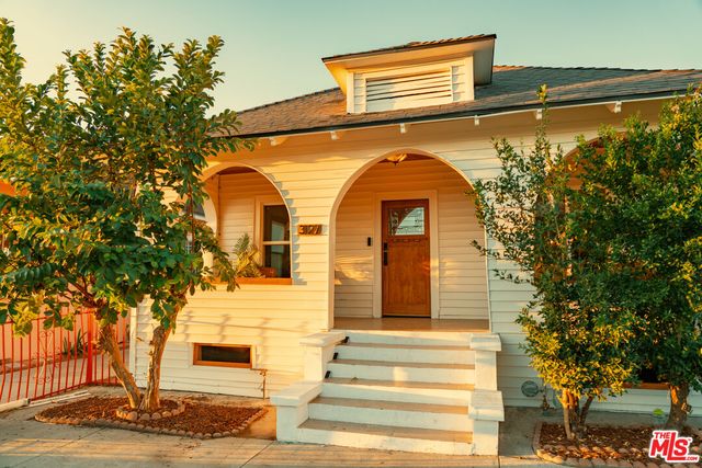 a front view of a house with a tree