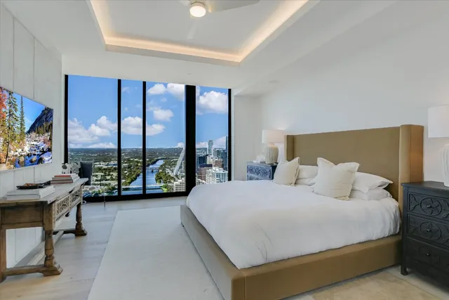 a bedroom with a bed and large windows