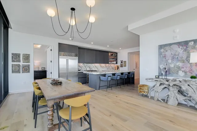 a kitchen with stainless steel appliances a dining table chairs stove refrigerator and cabinets