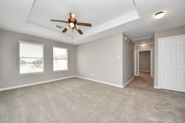 an empty room with windows and ceiling fan