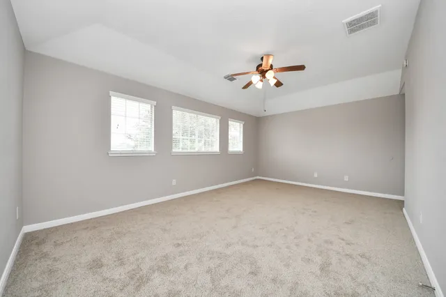 an empty room with windows and chandelier fan