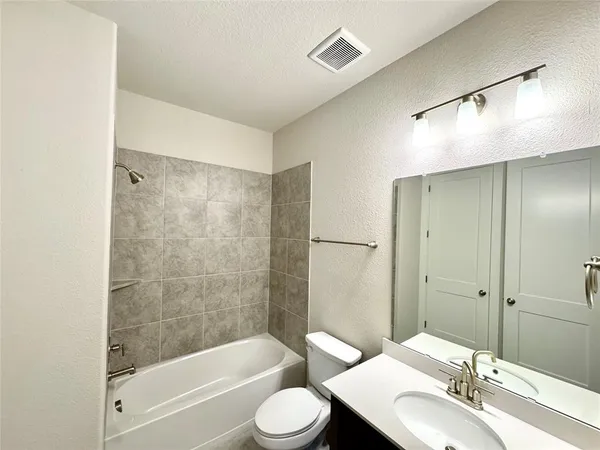 a bathroom with a bathtub shower sink vanity and toilet