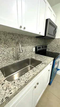 a kitchen with granite countertop a sink and a microwave