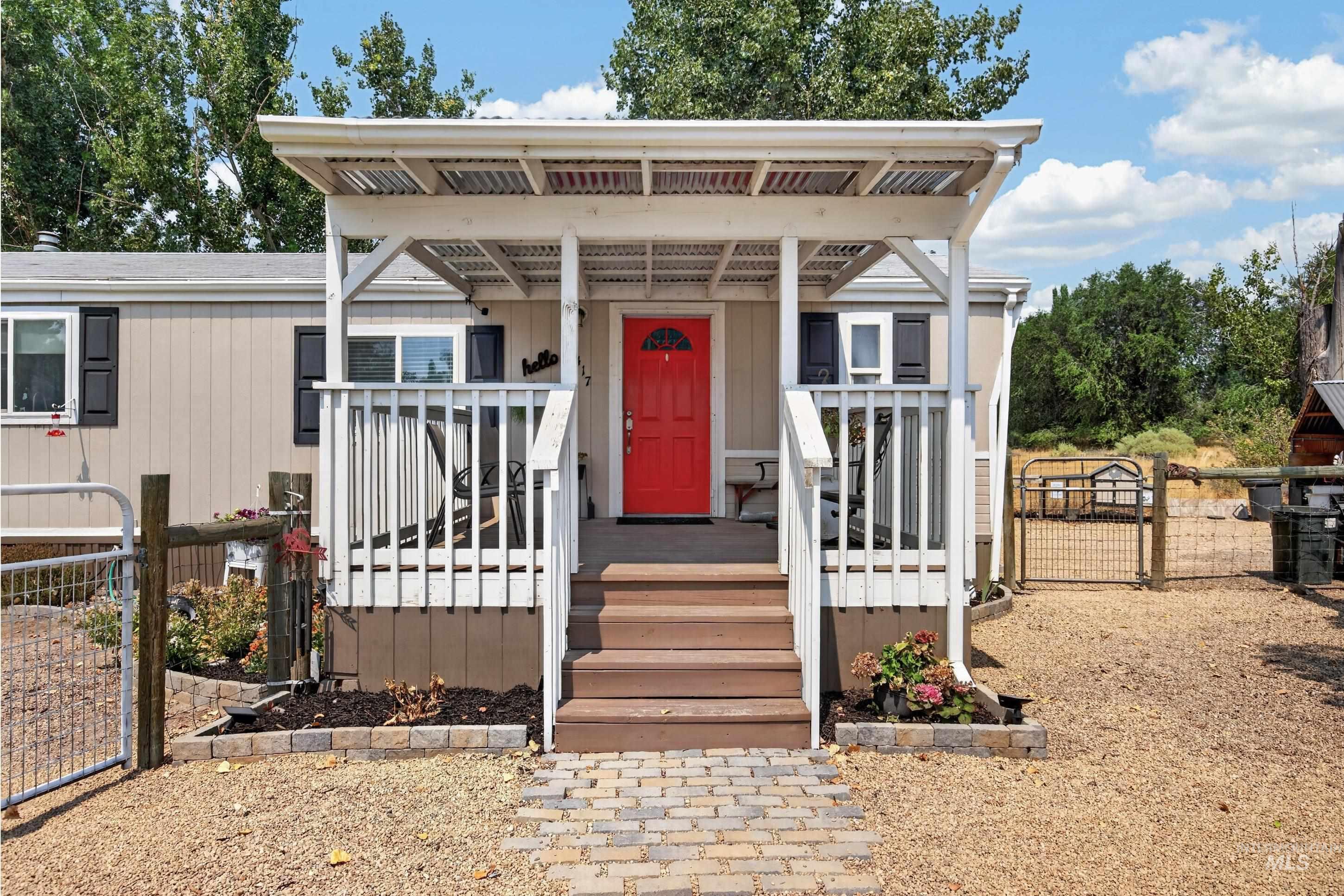 7417 Map Rock Road Caldwell, ID 83607 - Photo 4 of 32 Front entry with a covered porch, wood stairs, white railings, and a bold red door