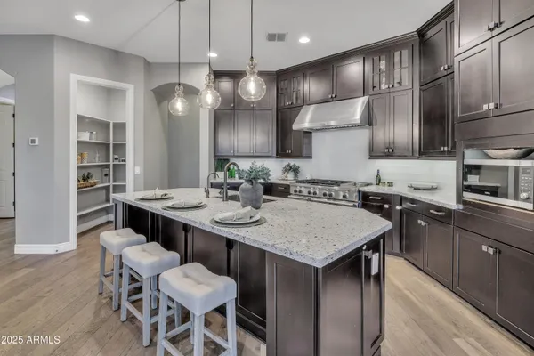 a kitchen with granite countertop a sink a center island stainless steel appliances and cabinets
