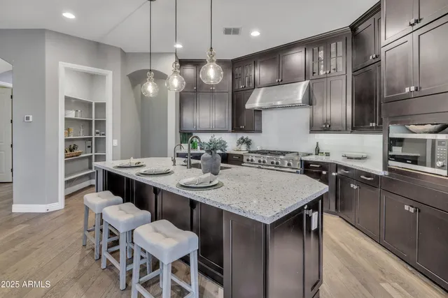 a kitchen with granite countertop a sink a center island stainless steel appliances and cabinets