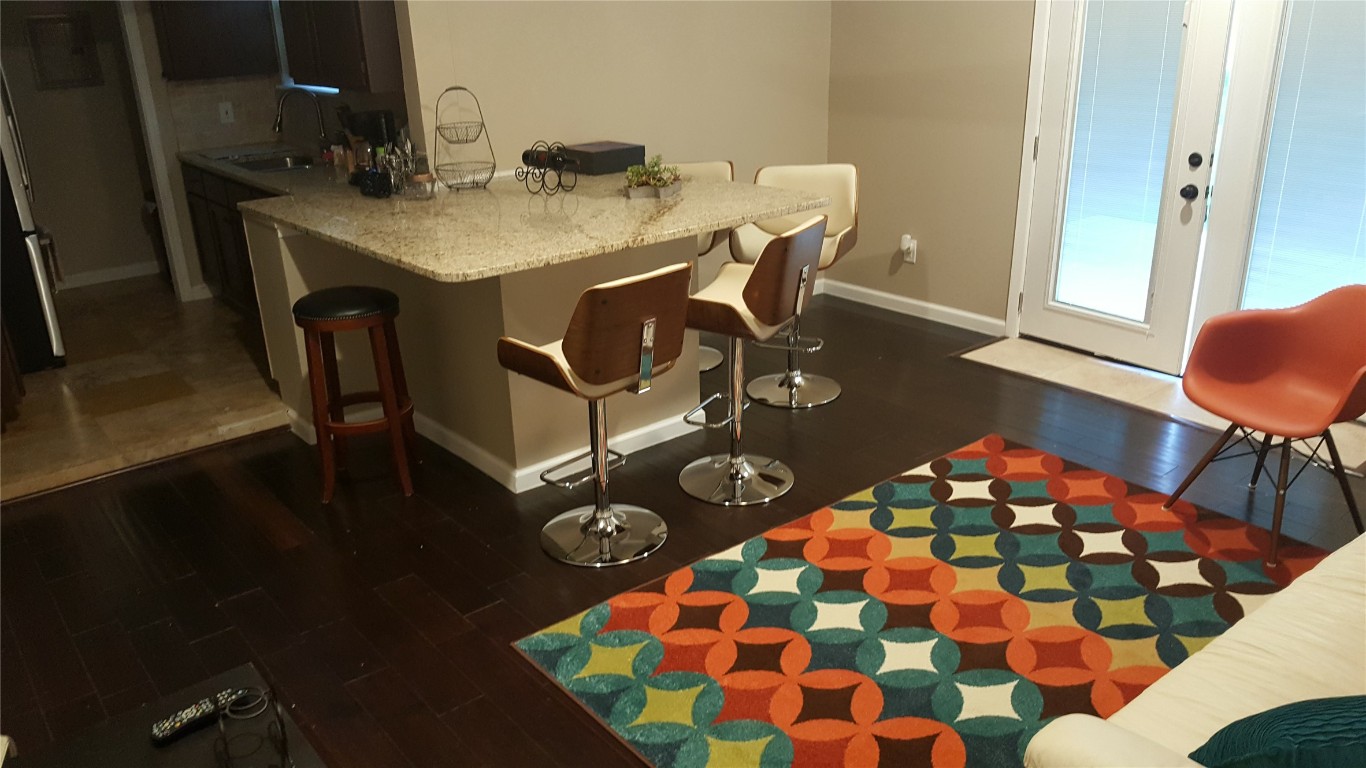 12410 Twin Creek Road Manchaca, TX 78652 - Photo 29 of 32 Kitchen featuring decorative backsplash, baseboards, a kitchen bar, dark wood finished floors, and a sink