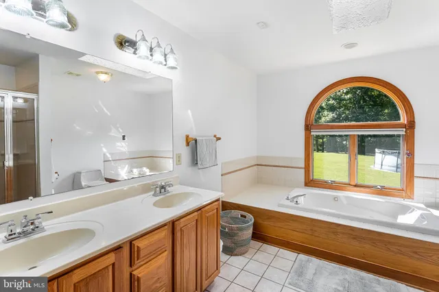 a bathroom with a granite countertop sink a large mirror a bathtub and a window