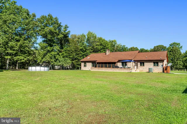 a view of a big house with a big yard and large trees