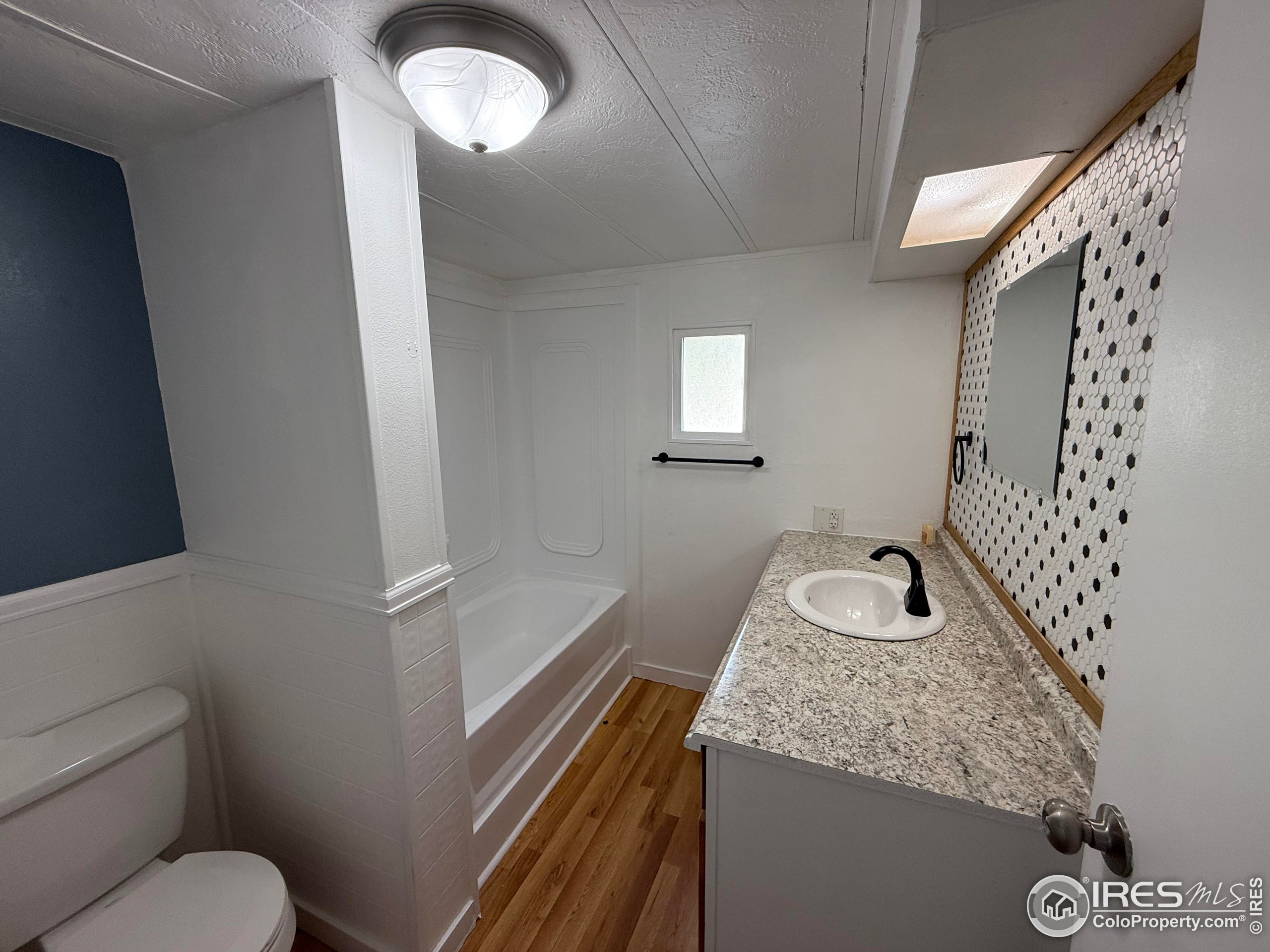 830 1st Street, Unit 23 Pierce, CO 80650 - Photo 16 of 16 a bathroom with a granite countertop sink mirror vanity and toilet