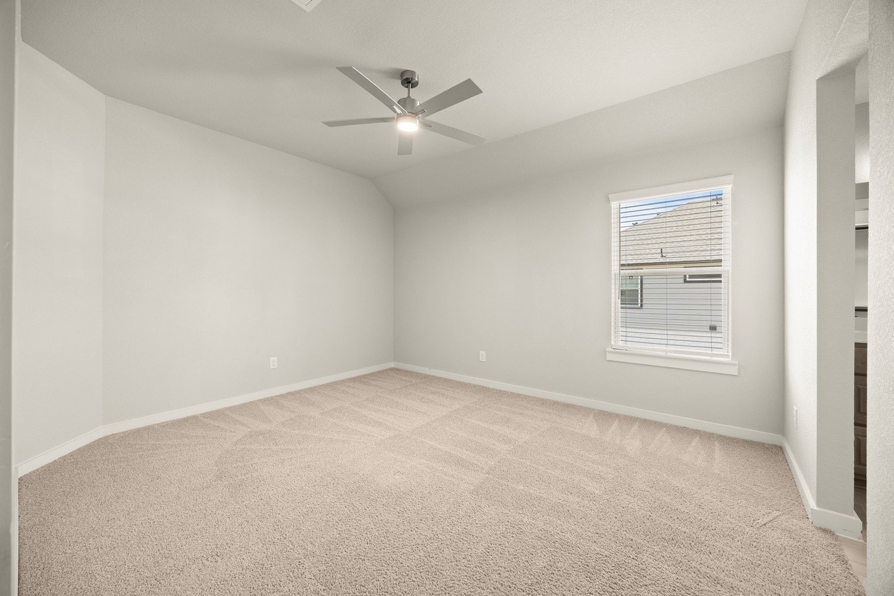 3018 North Spring Drive Spring, TX 77373 - Photo 21 of 25 Spacious room with plush carpeting, modern ceiling fan, and ample natural light from a large window, perfect for relaxation or a cozy retreat.