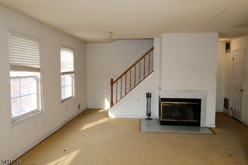 12 Rutgers Drive, Unit 12 Newark, NJ 07103 - Photo 9 of 22 a view of an empty room with wooden floor fireplace and a window