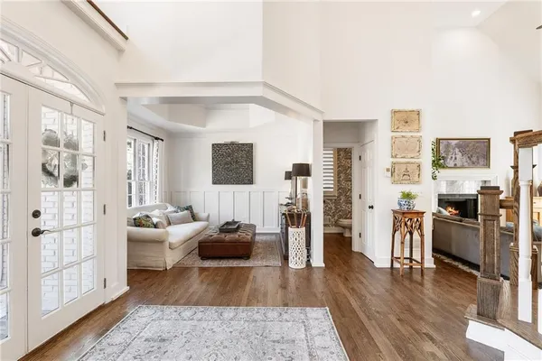 a living room with couches chairs and wooden floor next to a large window