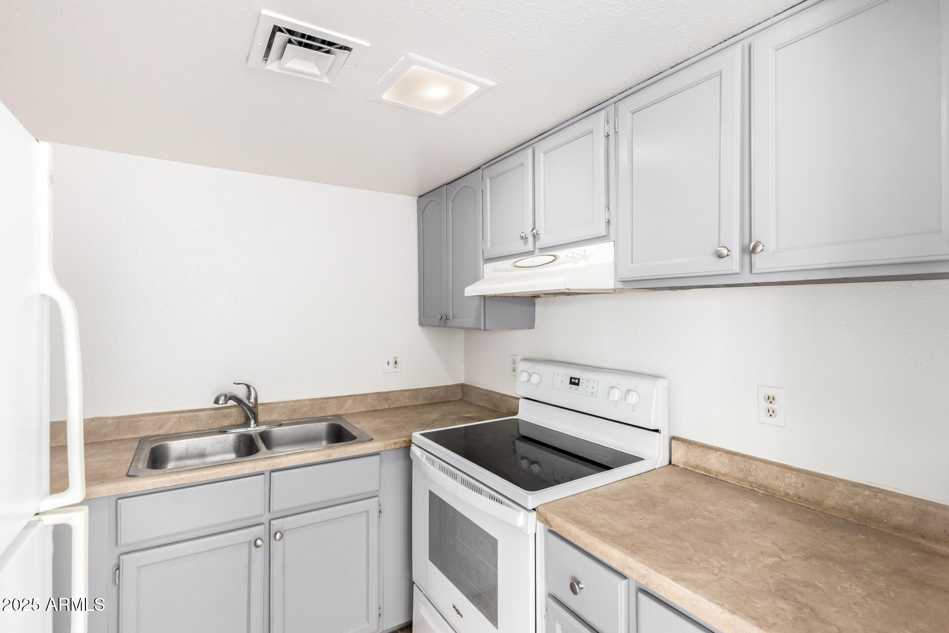 2674 North 43rd Avenue, Unit D Phoenix, AZ 85009 - Photo 8 of 19 a kitchen with white cabinets sink and stove