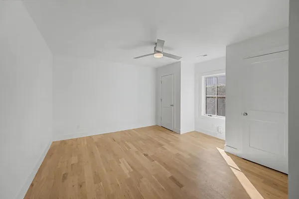 a view of empty room with wooden floor and ceiling fan