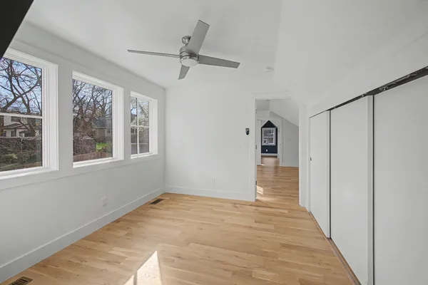 a view of empty room with wooden floor and fan