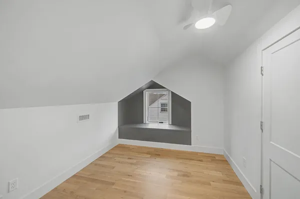 a view of an empty room with a window and wooden floor