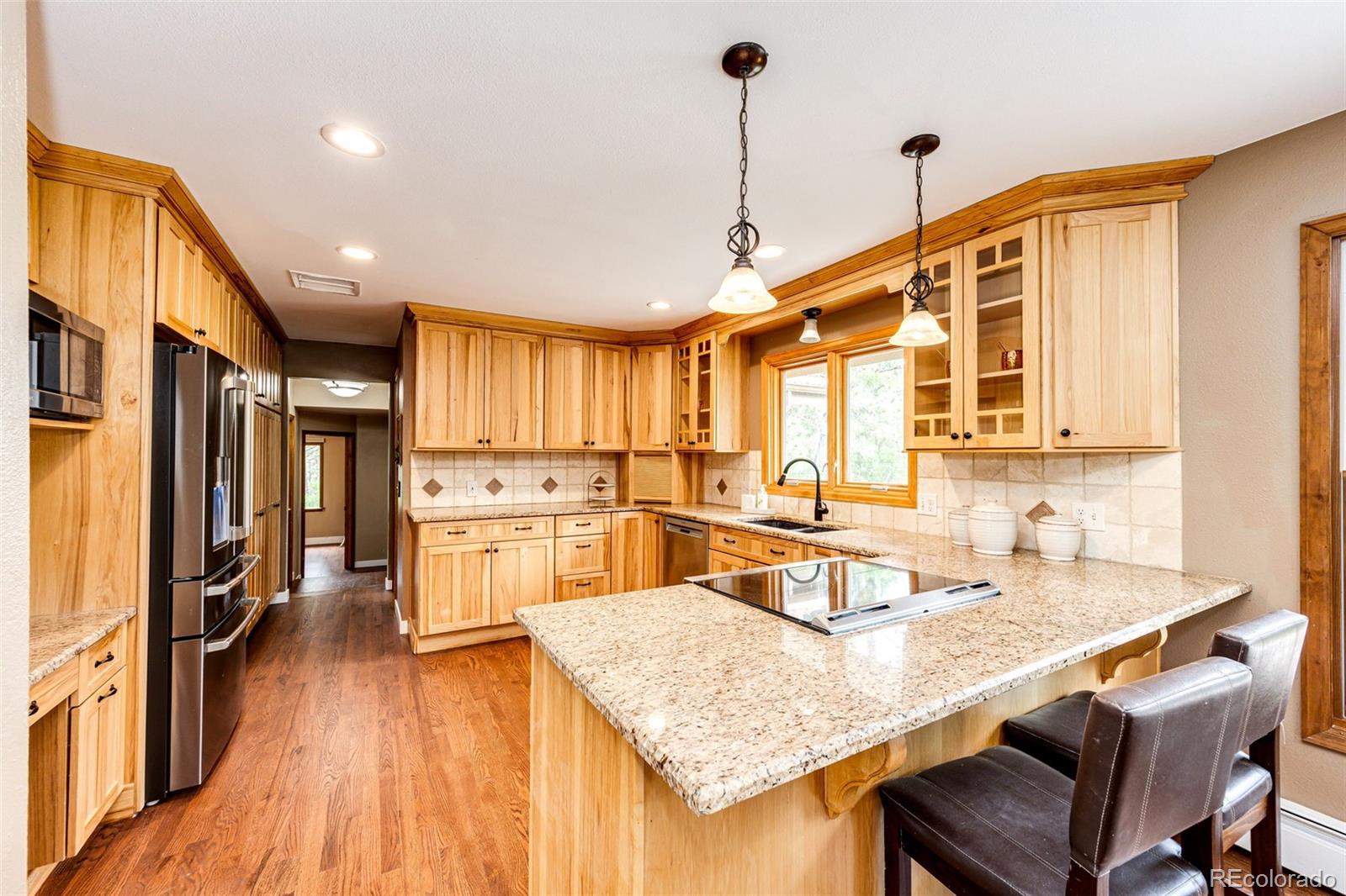 8788 East Tanglewood Road Franktown, CO 80116 - Photo 13 of 48 a kitchen with stainless steel appliances granite countertop a sink refrigerator and cabinets
