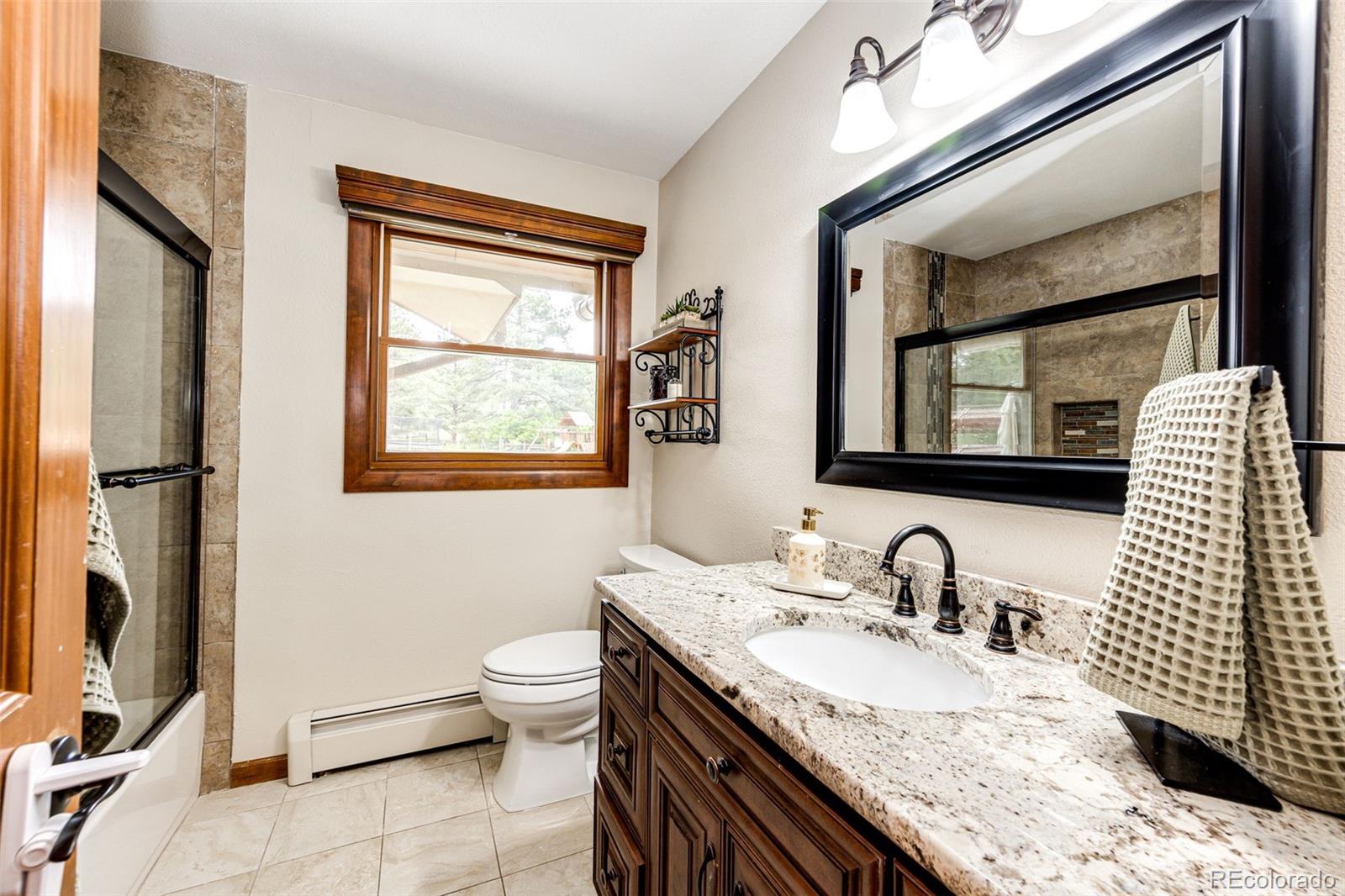 8788 East Tanglewood Road Franktown, CO 80116 - Photo 17 of 48 a bathroom with a granite countertop sink mirror vanity and toilet