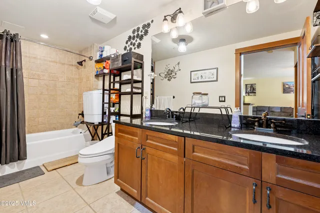 a spacious bathroom with a double vanity sink a toilet a mirror and shower