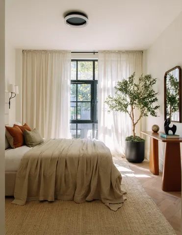 a bedroom with a large bed and a potted plant
