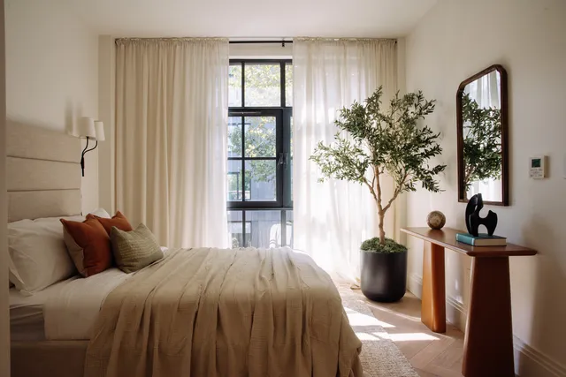 a bedroom with a bed and a potted plant next to a window