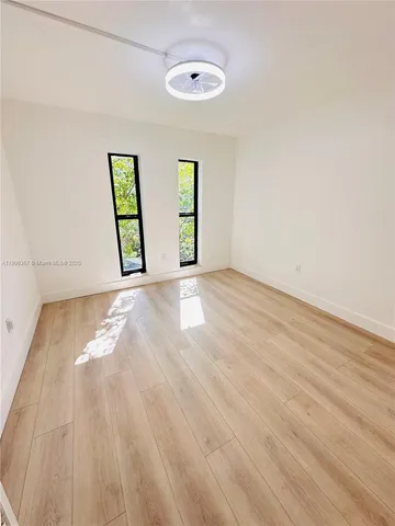 a view of an empty room with window and wooden floor