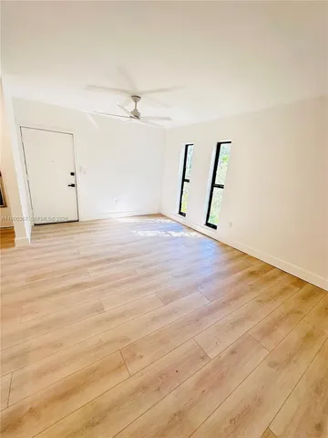 an empty room with wooden floor and ceiling fan