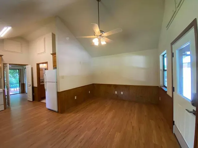 a view of an empty room with wooden floor and a window