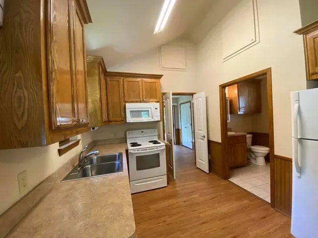 a kitchen with stainless steel appliances granite countertop a refrigerator a stove and a sink with wooden floor