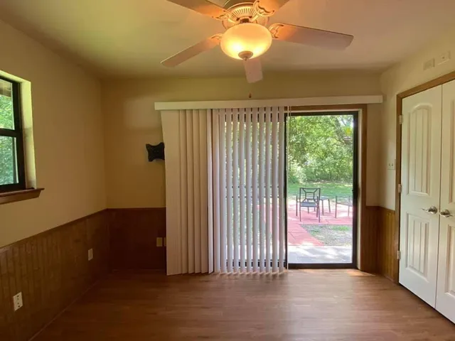 an empty room with wooden floor fan and windows
