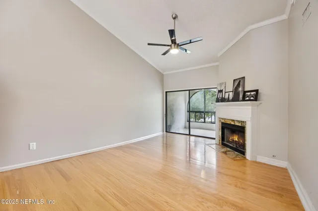 a view of an empty room with wooden floor fireplace and a window