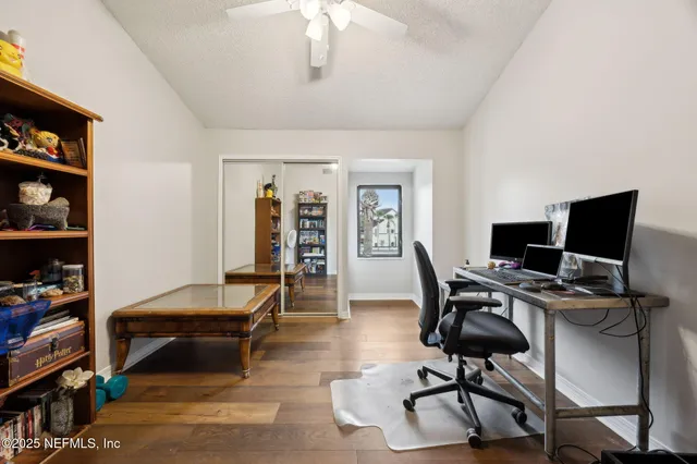 an empty room with wooden floor fan and windows