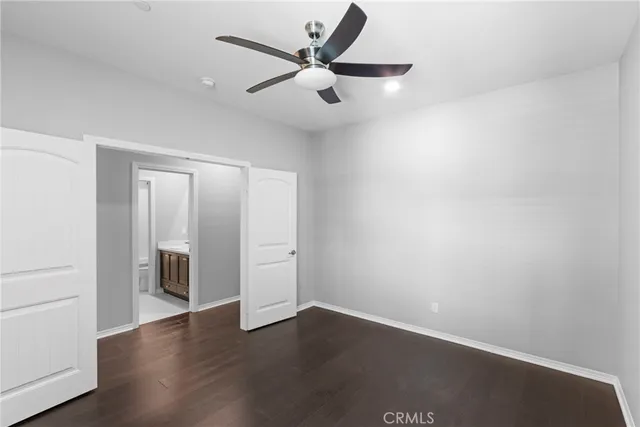 an empty room with wooden floor ceiling fan and windows