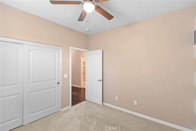an empty room with a ceiling fan and carpet