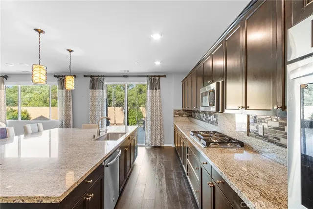 a kitchen with stainless steel appliances granite countertop a sink a stove and a wooden floors