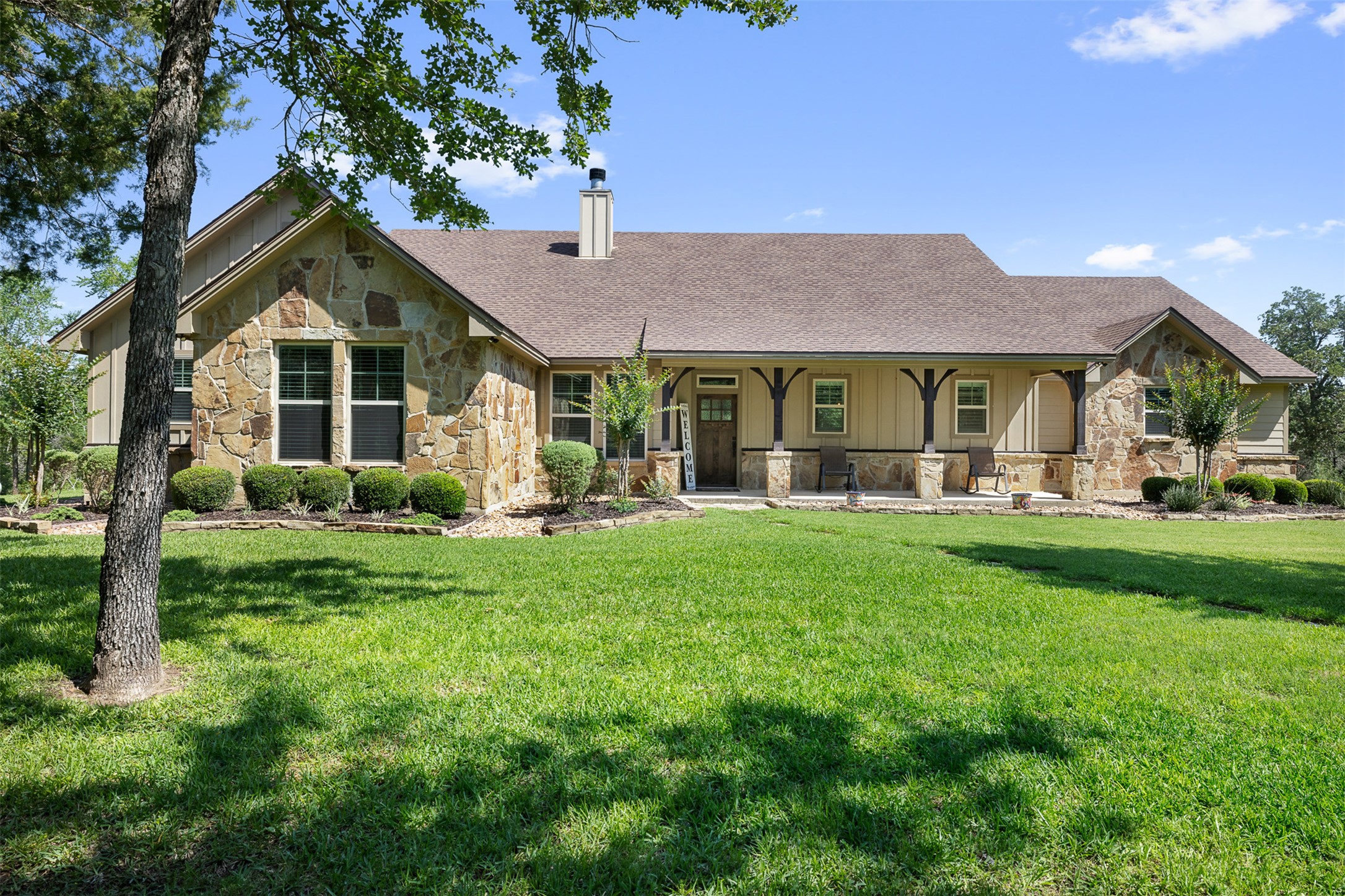 1306 22 Hills Road Gause, TX 77857 - Photo 30 of 40 Stone and siding exterior with a covered front porch featuring exposed beams, decorative columns, and a prominent chimney