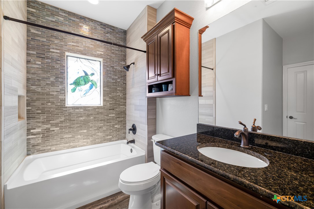 559 West Lago Loop Road Port O'Connor, TX 77982 - Photo 22 of 44 a bathroom with a granite countertop sink a toilet a mirror and bathtub