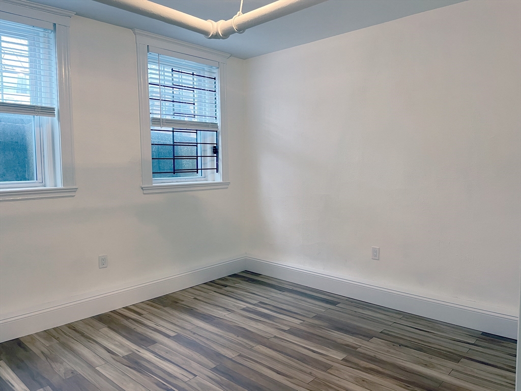 15 Thatcher Street, Unit B Brookline, MA 02446 - Photo 6 of 8 an empty room with wooden floor and windows