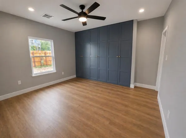 a view of an empty room with a window and wooden floor