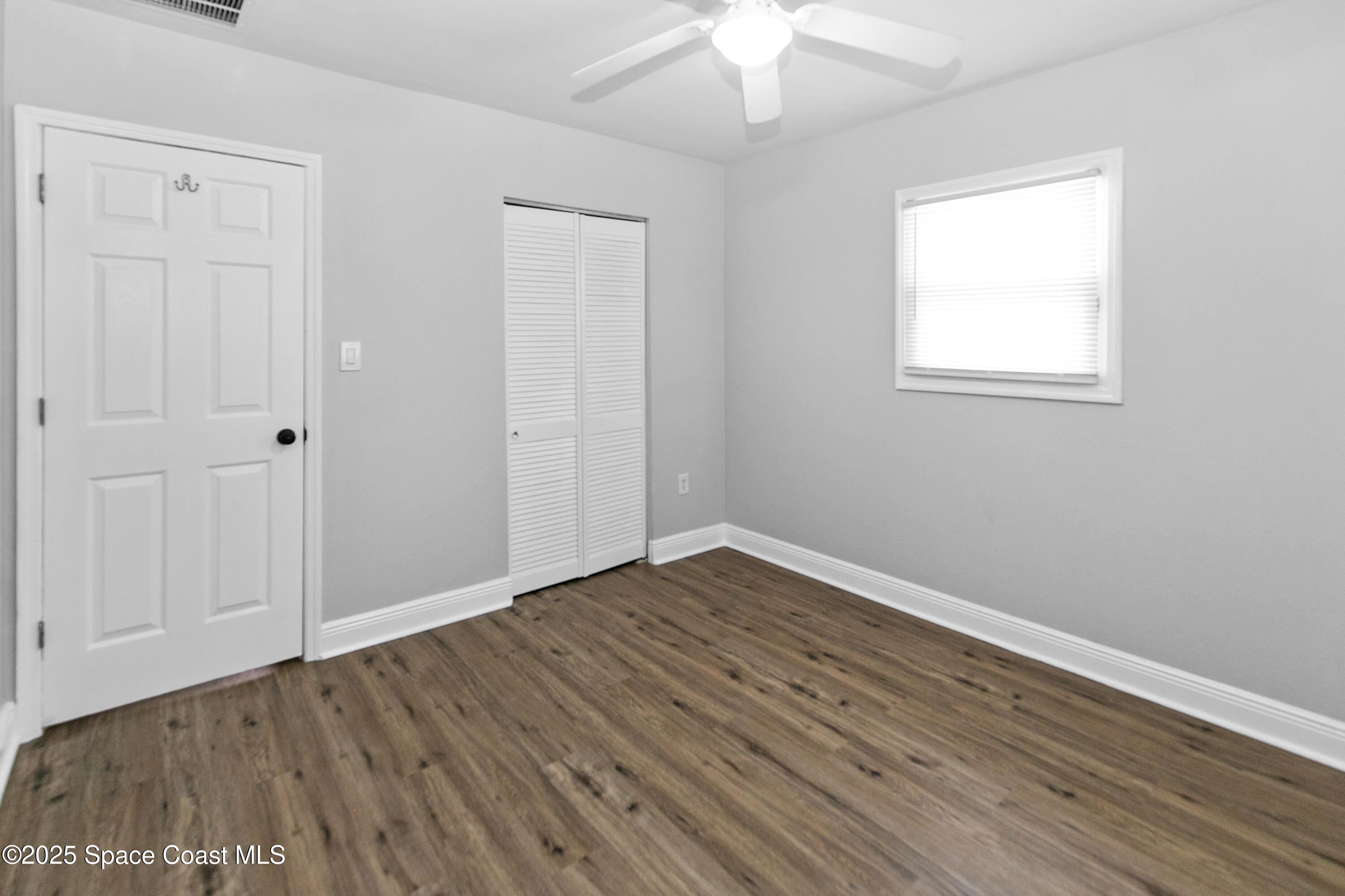 905 North Carpenter Road Titusville, FL 32796 - Photo 17 of 27 an empty room with wooden floor chandelier fan and windows