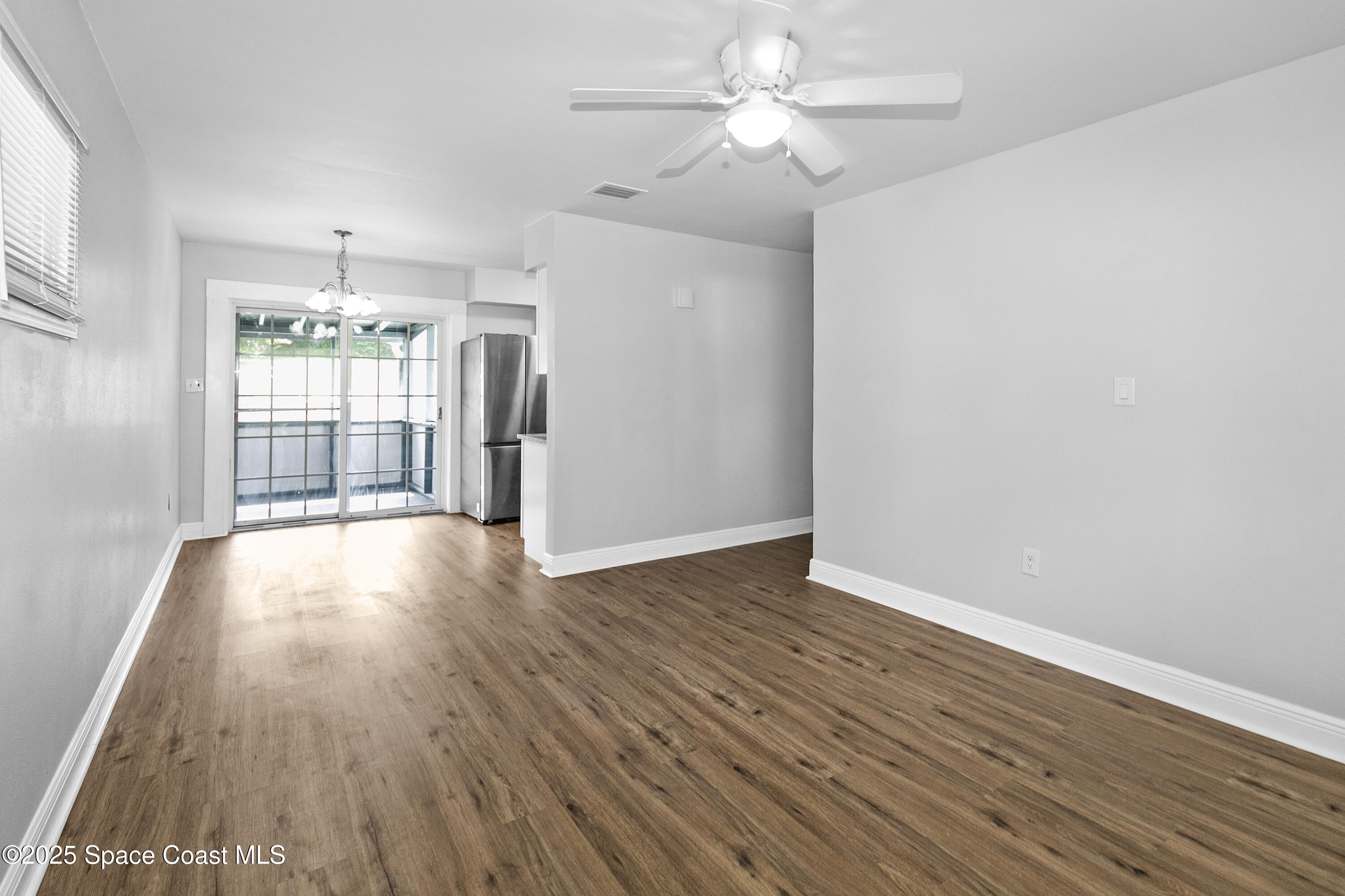 905 North Carpenter Road Titusville, FL 32796 - Photo 3 of 27 an empty room with wooden floor and windows