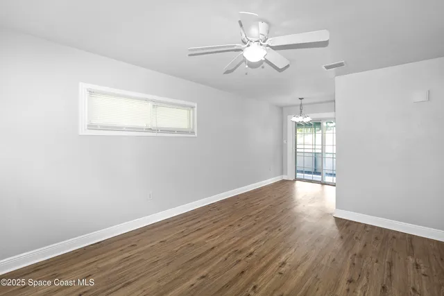 an empty room with wooden floor fan and windows