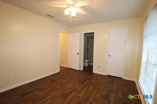 an empty room with wooden floor and a ceiling fan