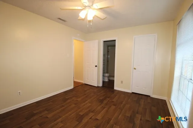 an empty room with wooden floor and a ceiling fan