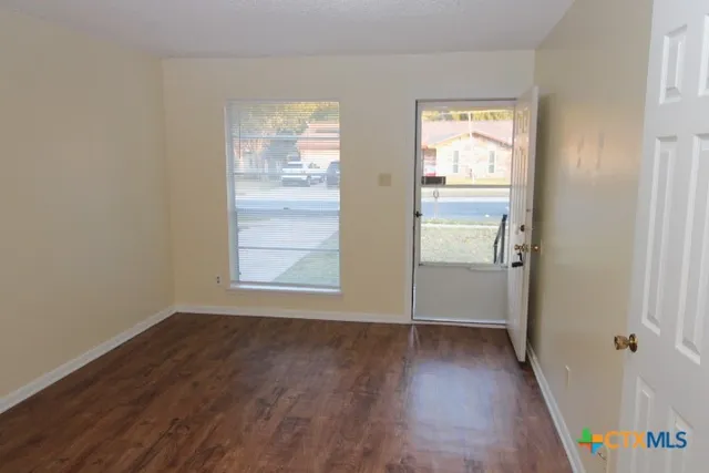 a view of an empty room with wooden floor and a window